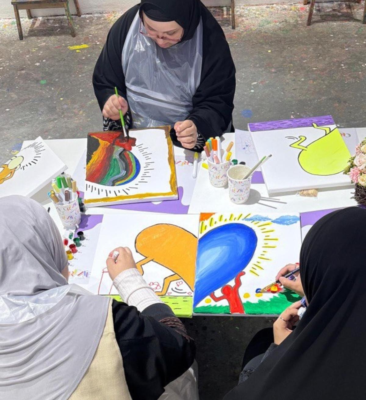 اصدقاء جالسون على الطاولة يقومون بتلوين مجسمت فنية